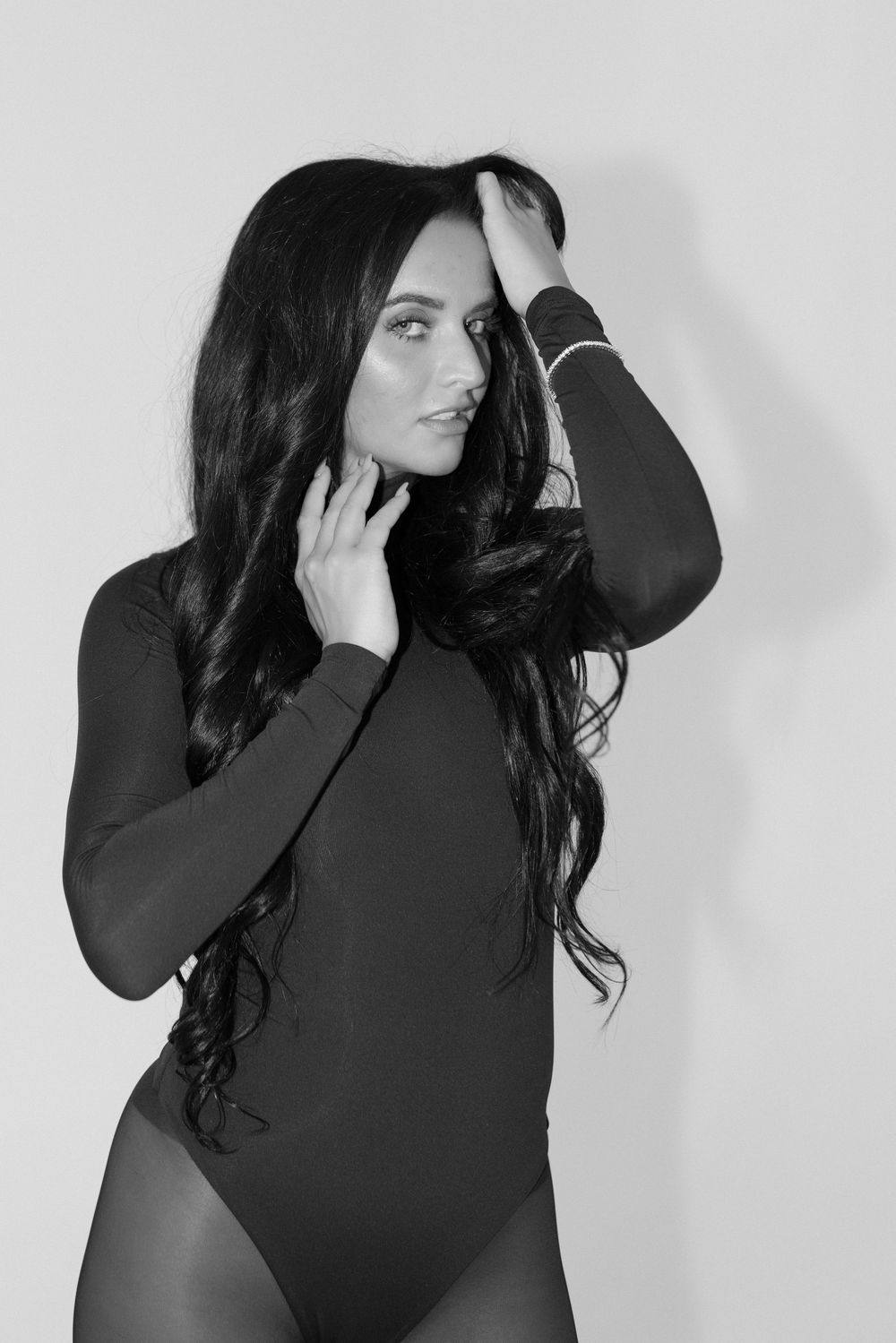 A series of four black and white fashion portraits showing a figure in a dark turtleneck against a light background.