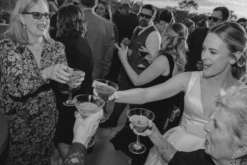 Wedding guests raise champagne glasses in celebration during a black and white reception toast moment.