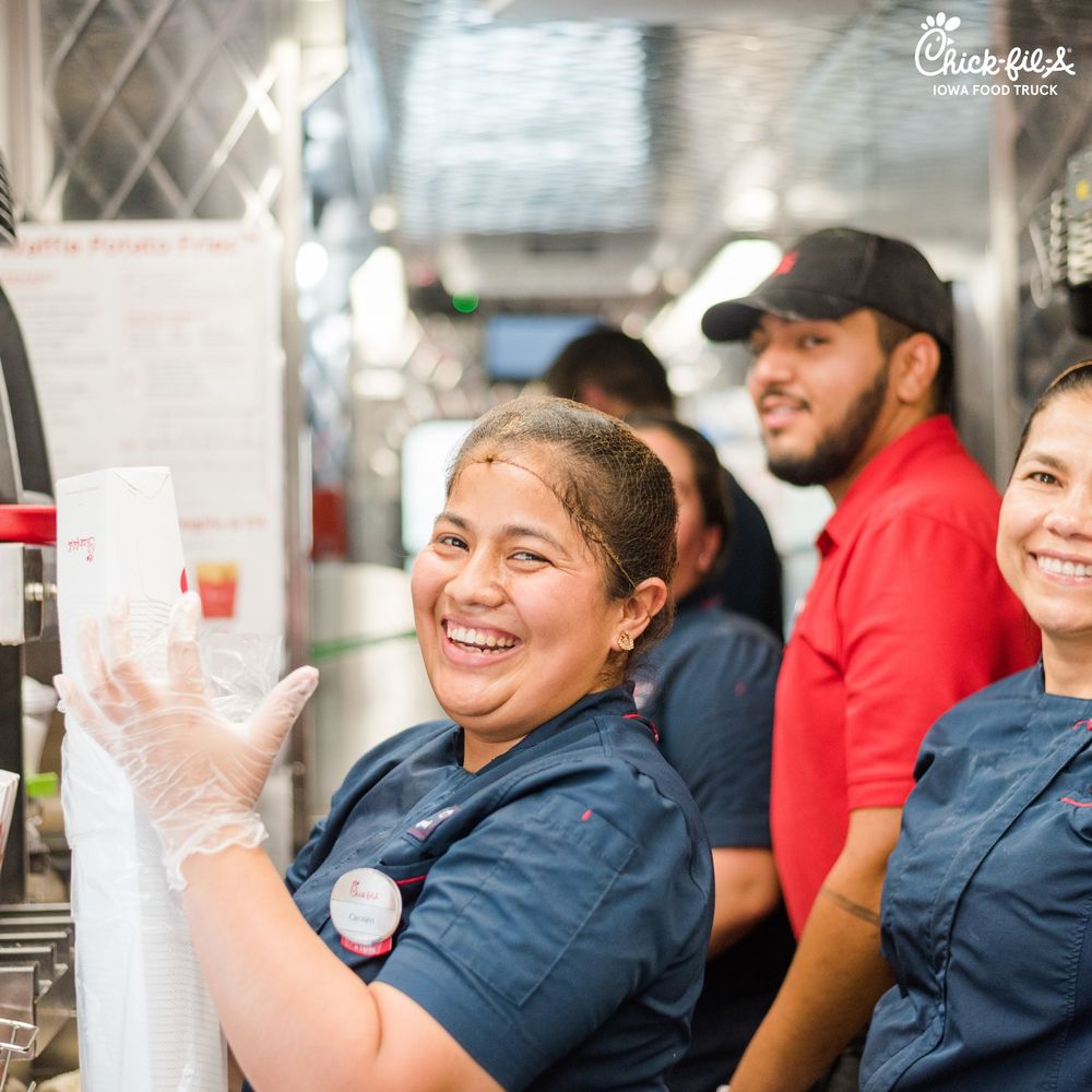 Restaurant staff members in navy uniforms sharing a lighthearted moment together.