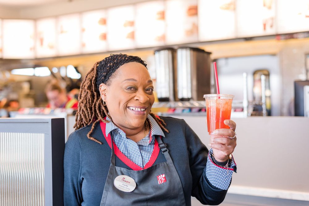 Restaurant employees in red and navy uniforms showing excitement while holding sauce packets.