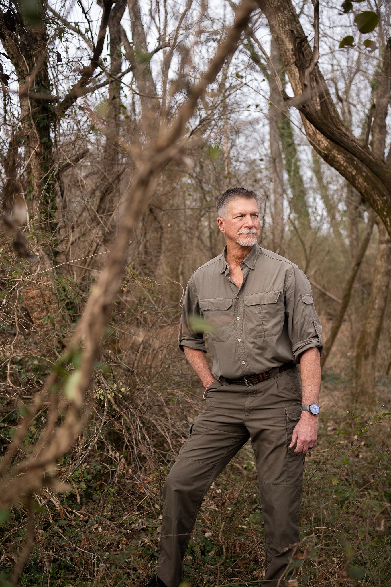 A person in khaki outdoor clothing poses against a wooded forest backdrop in a series of casual nature shots.