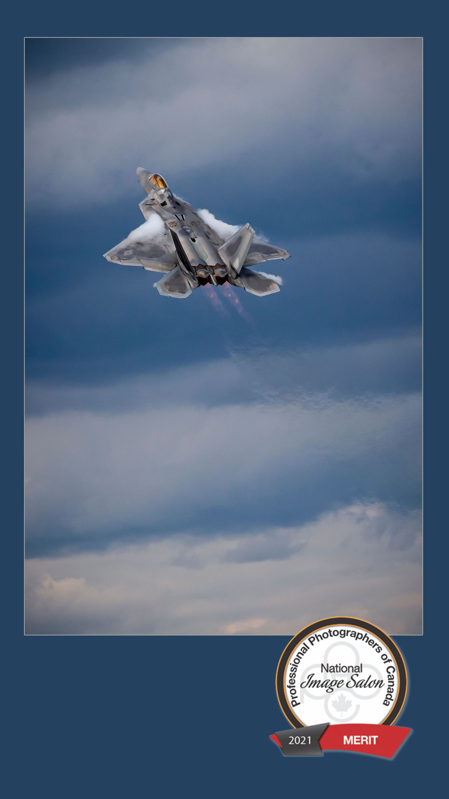 Military jet creating a vapor cone during a high-speed sonic boom maneuver against a blue sky.