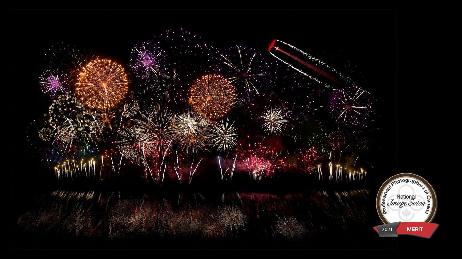 Composite image of fireworks at the Oshkosh Air Show, reflected on water, recognized at the 2021 PPOC national image salon.