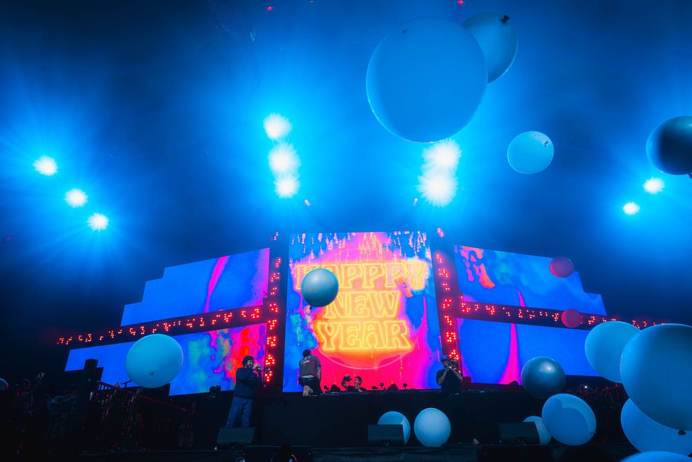 Concert stage illuminated with vibrant blue and pink lights creating a dramatic atmosphere during a live performance.