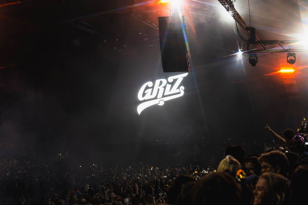Concert stage illuminated with bright orange spotlights and fog effects during a nighttime performance.
