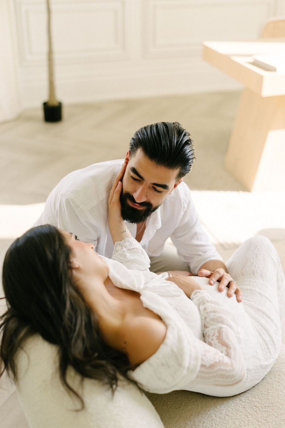 Expectant couple lying together on a studio floor.