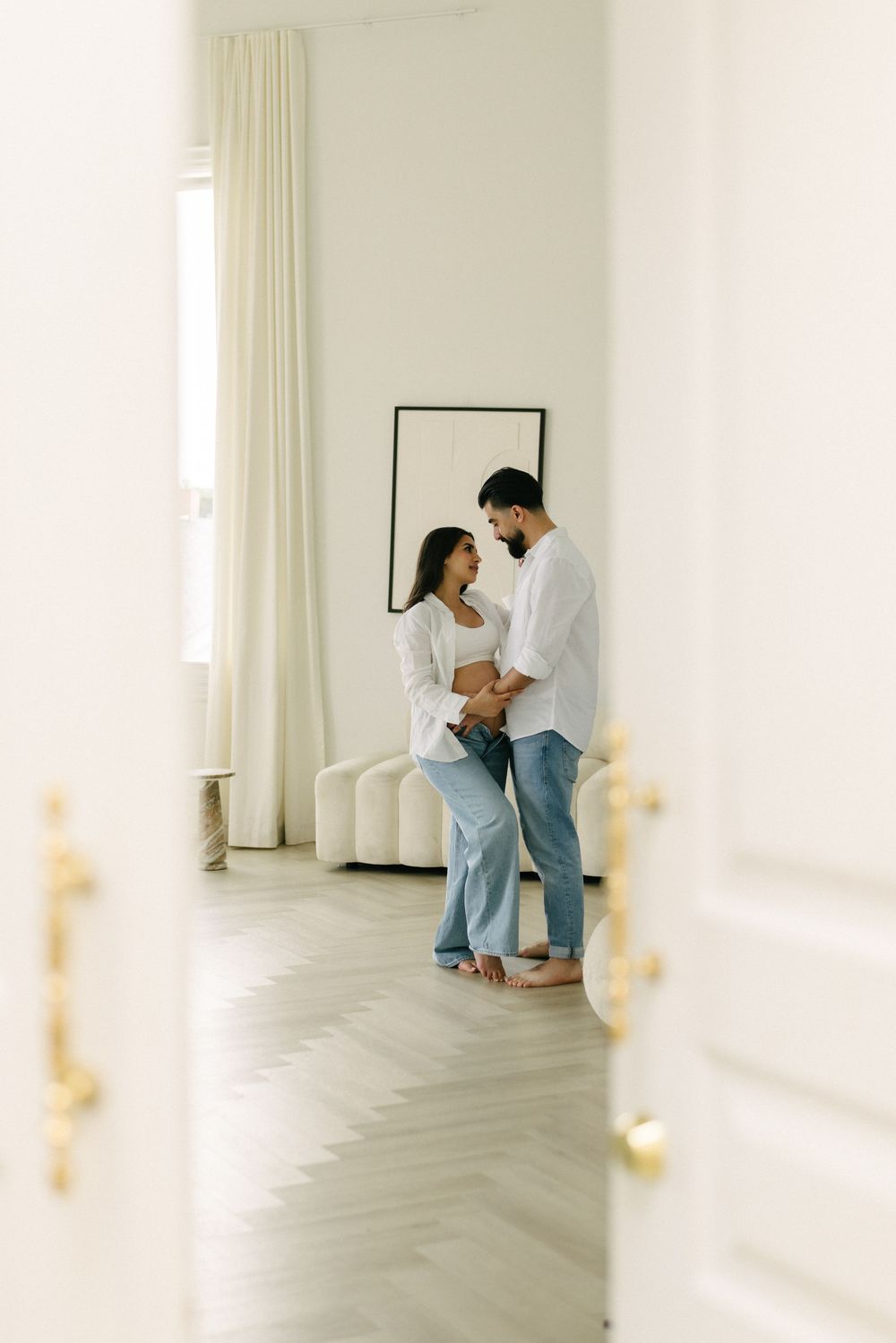Expectant couple standing in a bright empty room.