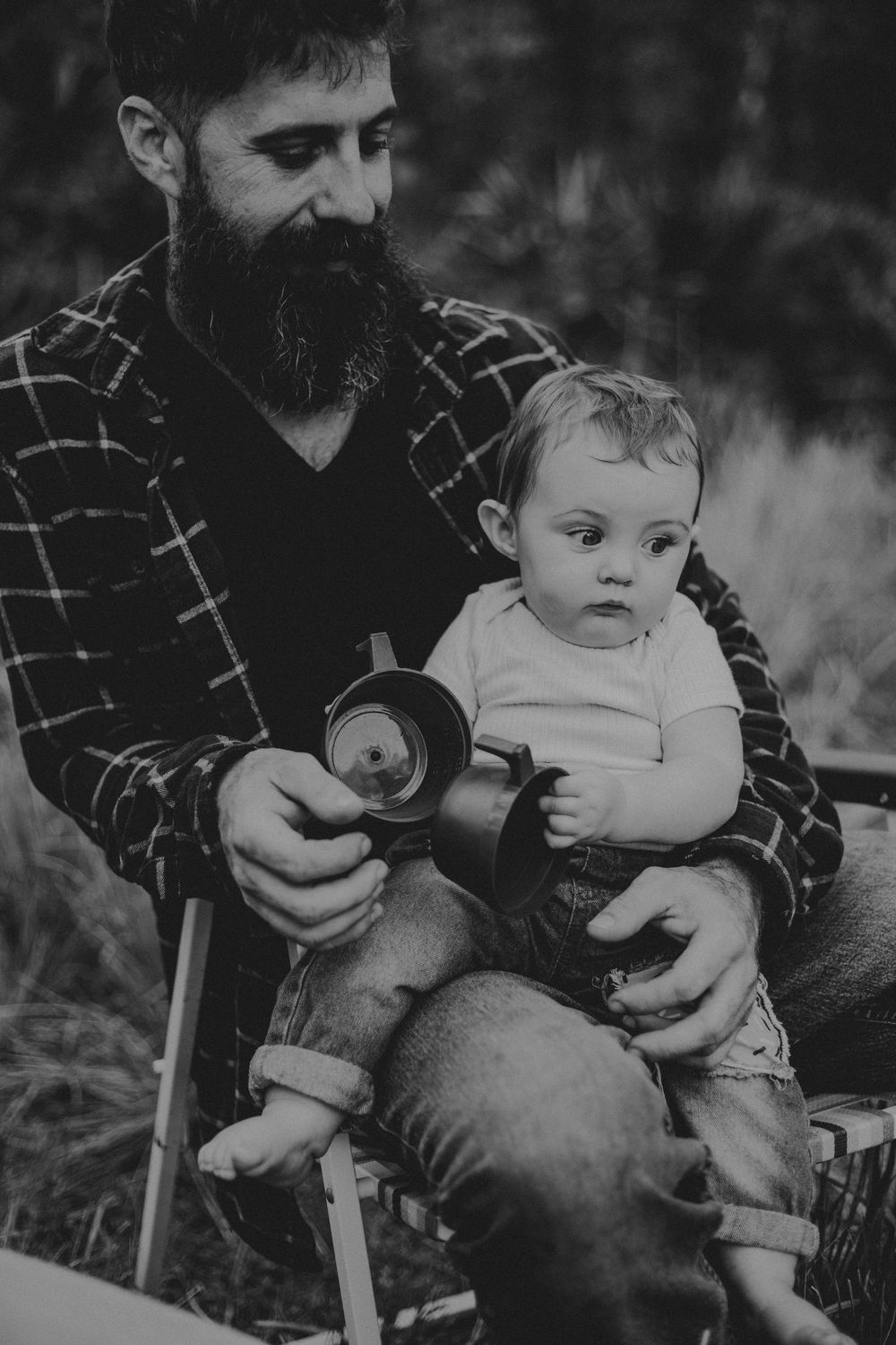 A black and white photo series showing tender moments between a parent and baby sitting together outdoors.