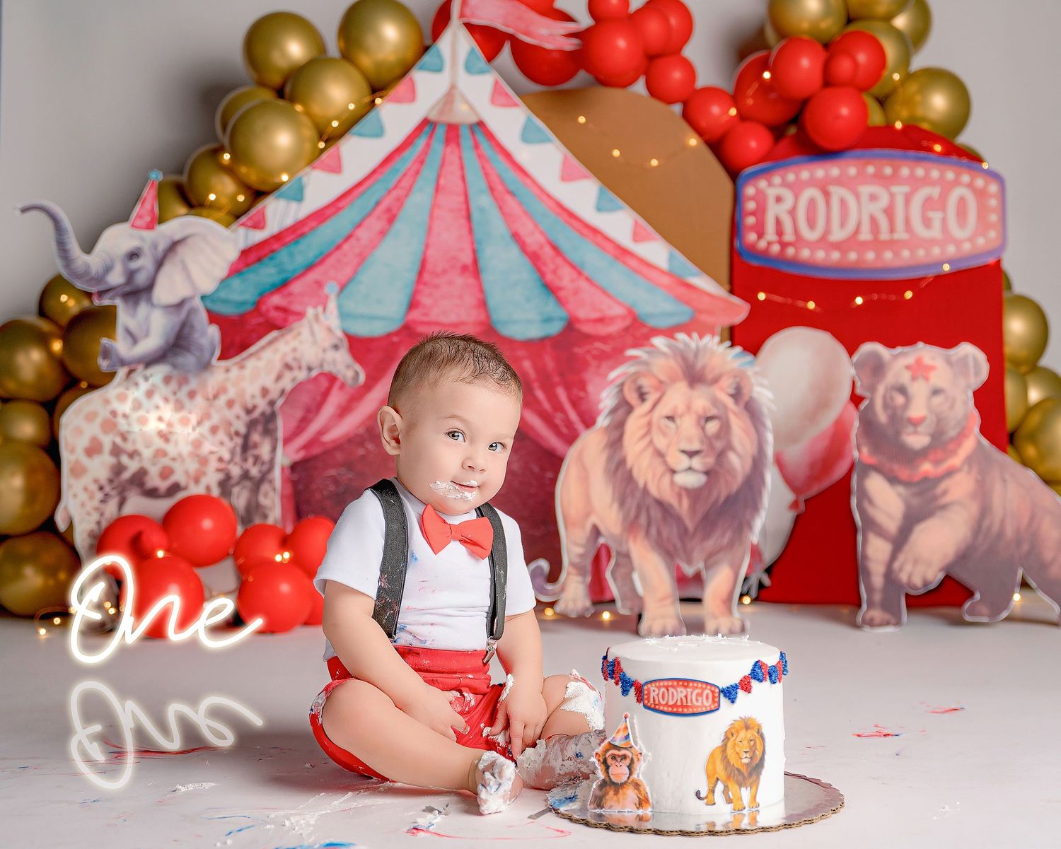 Circus-themed first birthday party setup with red and gold balloons, carousel decorations, and smash cake.