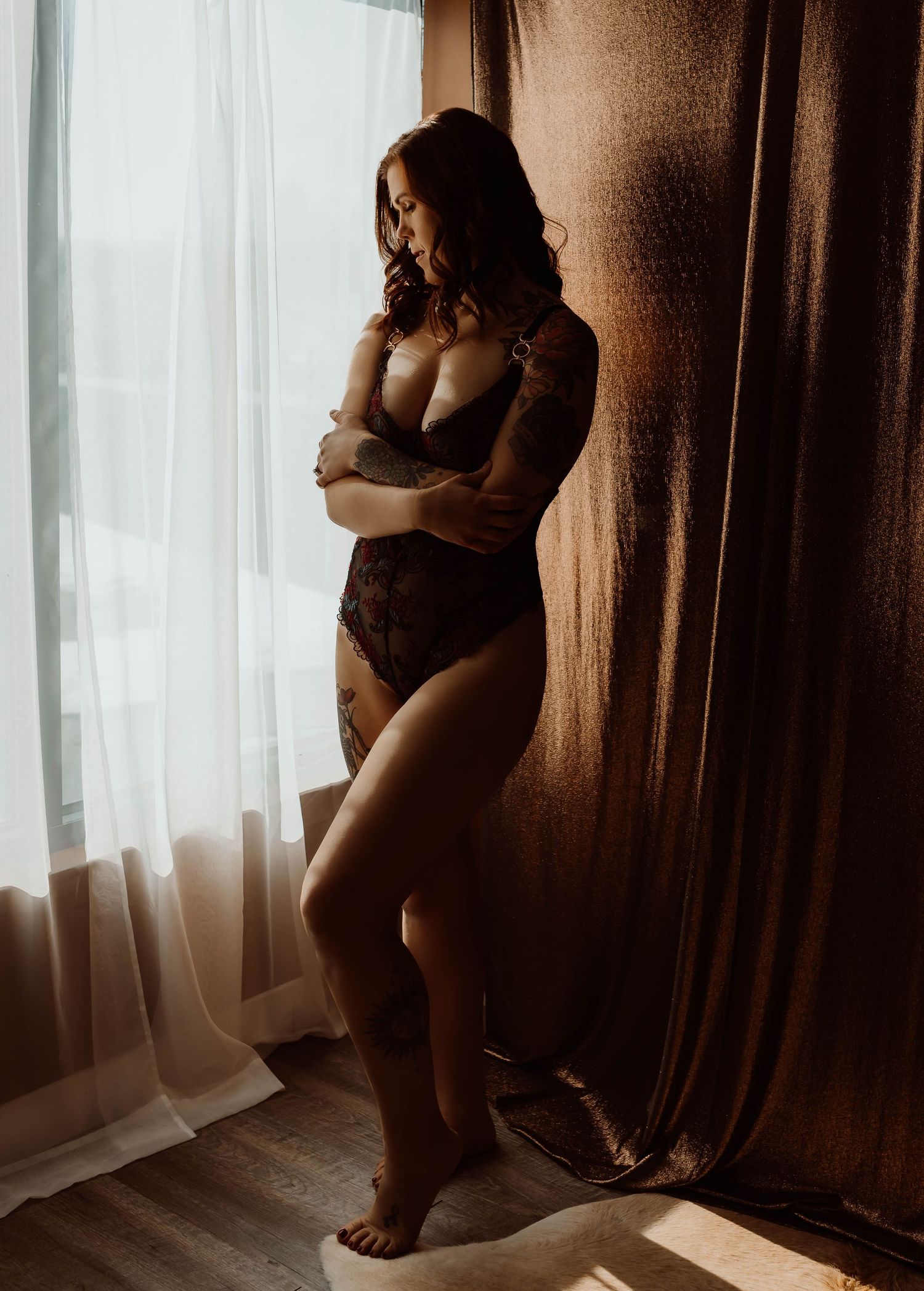 Artistic maternity silhouette boudoir photography series showing a woman by window in warm moody lighting by Boudoir by KJ.