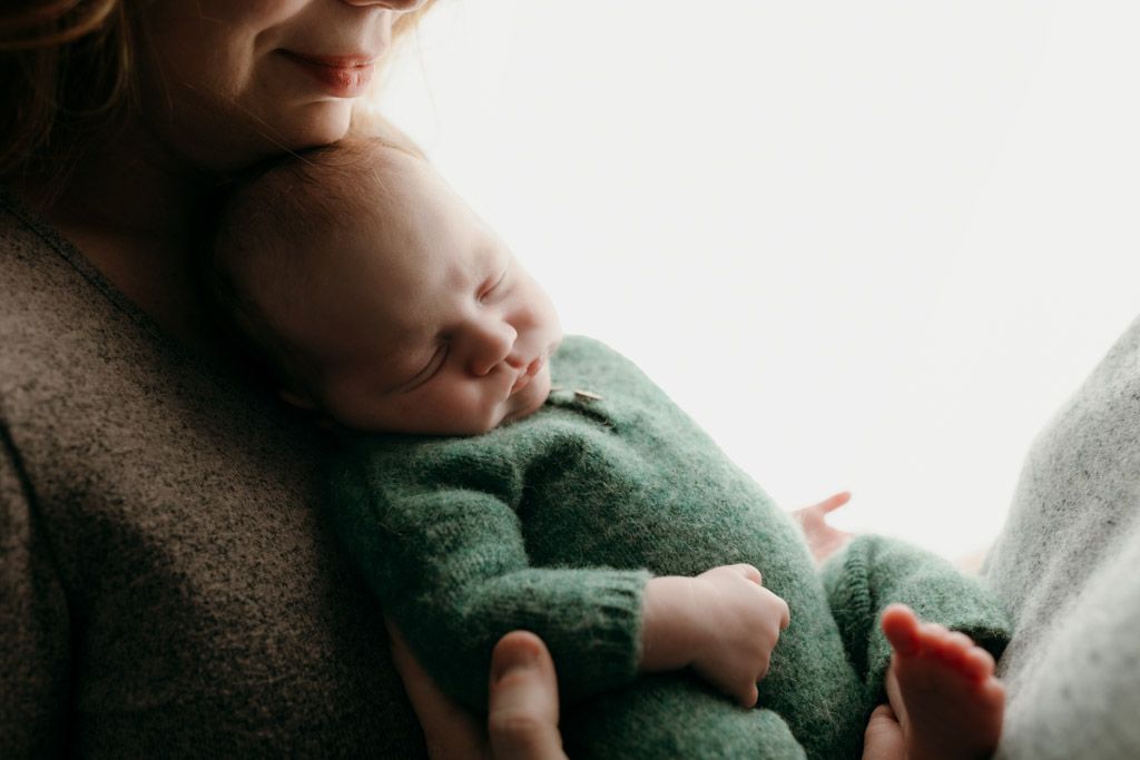A photo of sleeping newborn baby swaddled in white fabric lies peacefully on a blanket done by studio in Victoria BC newborn photographer