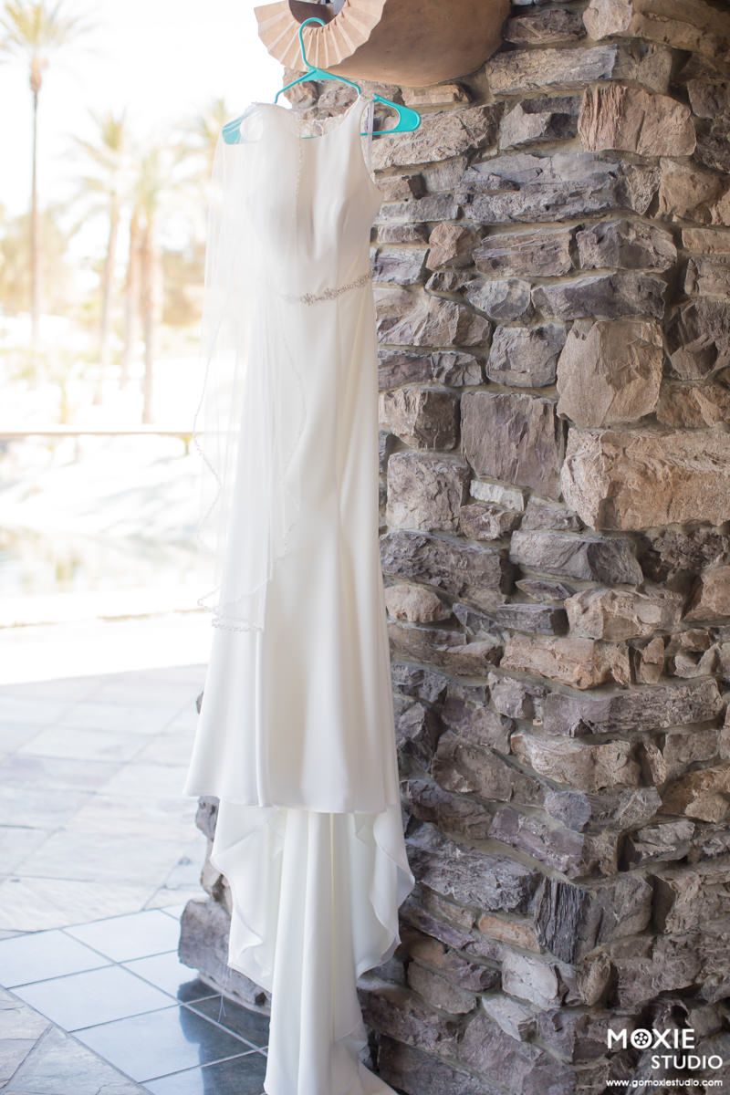 White wedding dress photographed against rustic stone wall in elegant bridal portrait session.