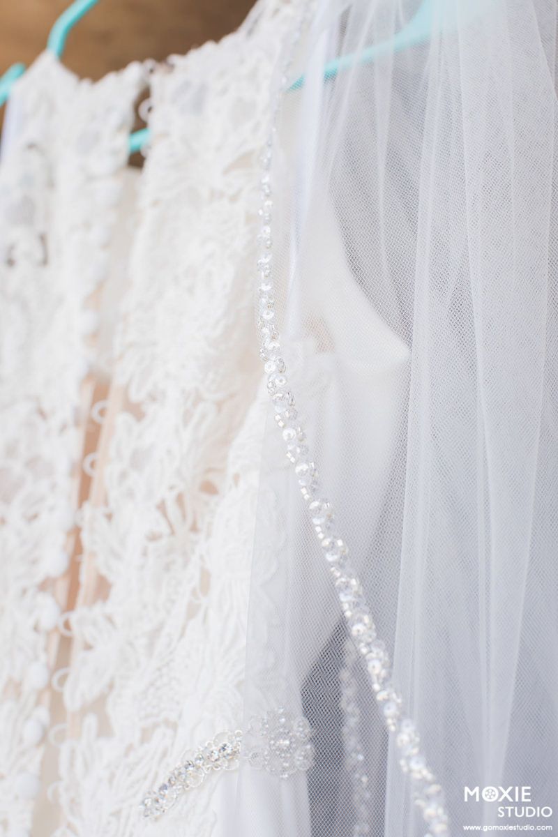 Close-up details of delicate white lace and tulle fabric from a wedding dress with intricate floral patterns.