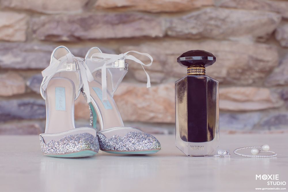 A series of baby shoes and decorative items arranged artistically against a rustic stone wall background.