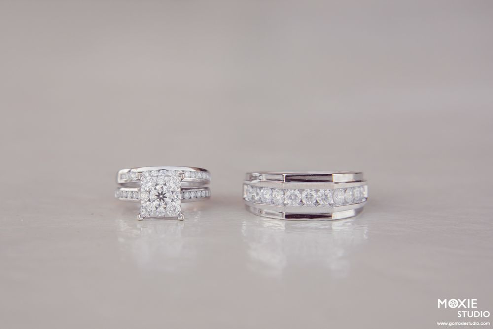 A collection of elegant diamond engagement rings and wedding bands displayed in a row on a light gray surface.
