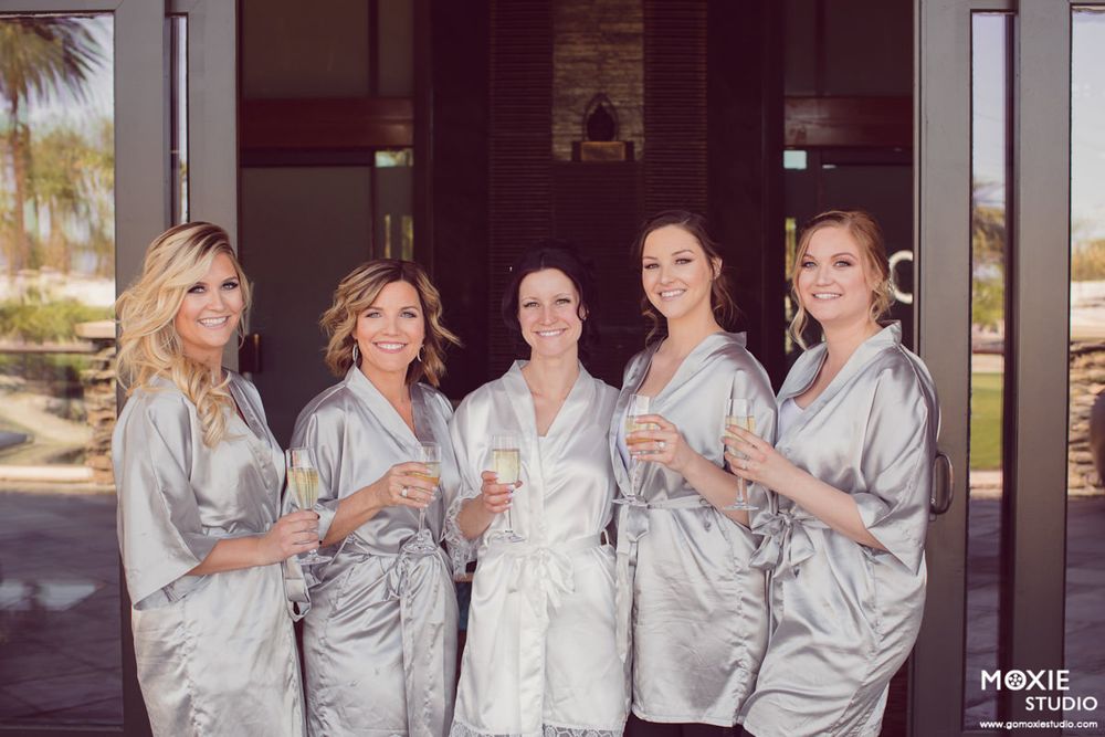 A group wearing matching silver satin robes poses together during a wedding preparation photoshoot.