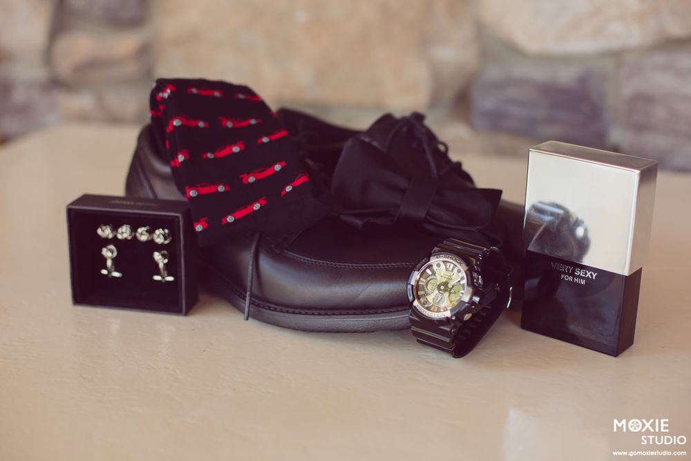 Wedding accessories including bow ties, watches, and jewelry arranged on a dark surface.