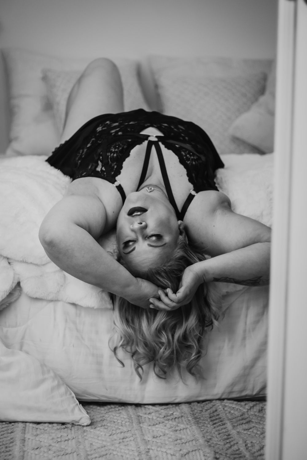 Black and white boudoir photo of woman in lace on bed. Boudoir photography