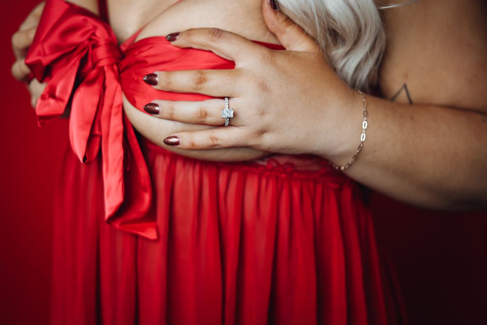 Close-up maternity boudoir showing red dress with bow detail. Boudoir photography