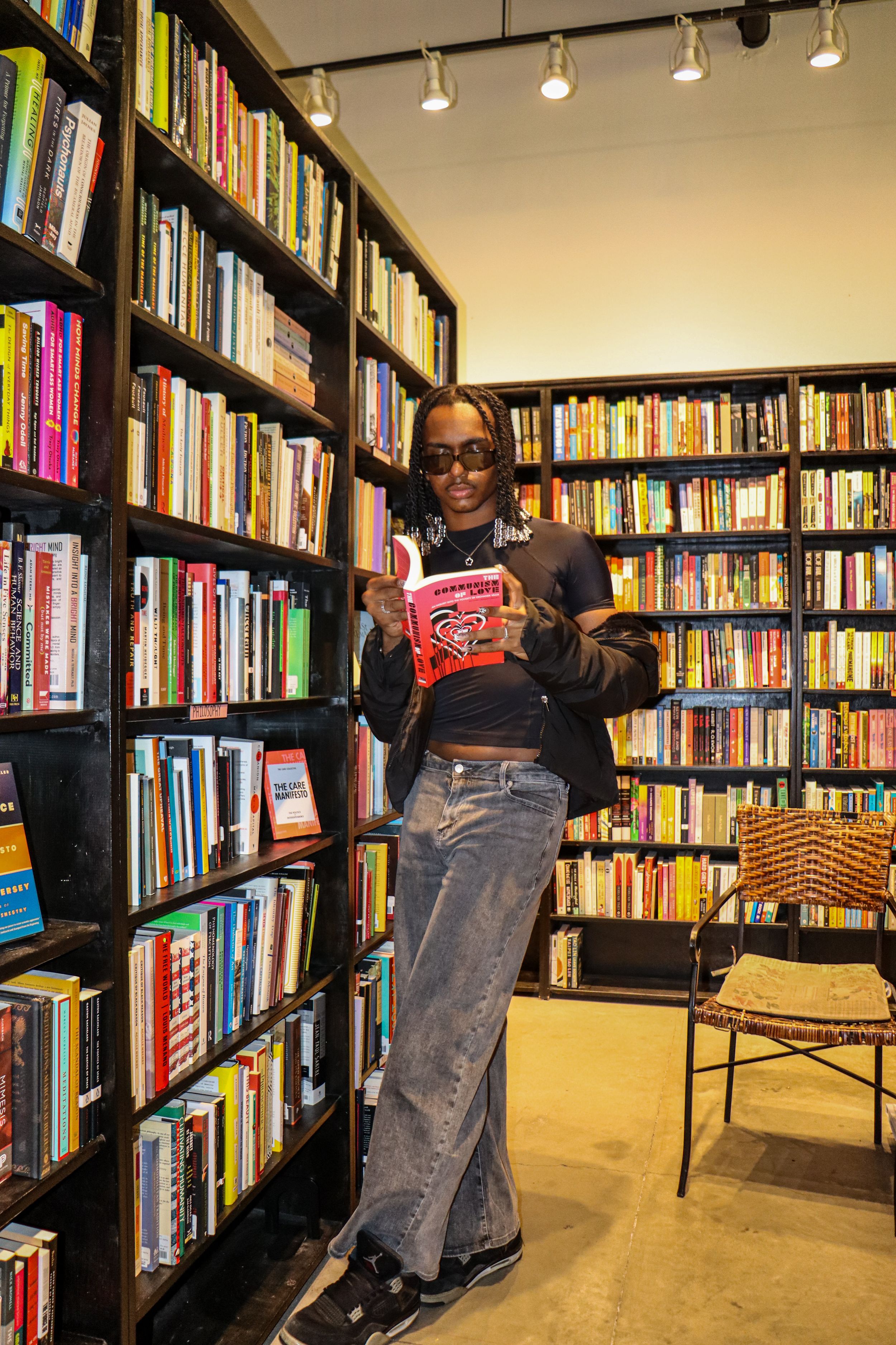 Person browses books while standing in cozy bookstore with warm lighting.