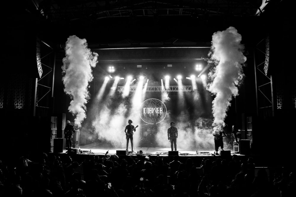 Rock concert stage with dramatic smoke effects and bright spotlights.