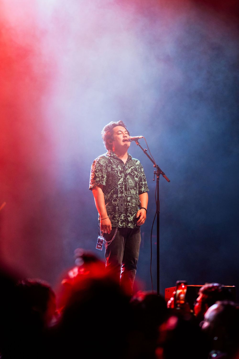 Performer singing on stage with dramatic red and blue lighting effects.