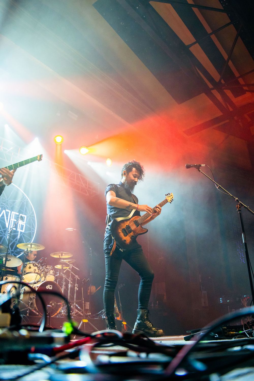 Musician plays guitar on stage with dramatic lighting and fog effects.