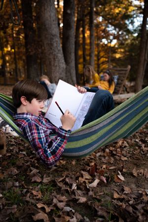 Memphis Family Photographer portrait of girl reading at Shelby Farms during Golden Hour.