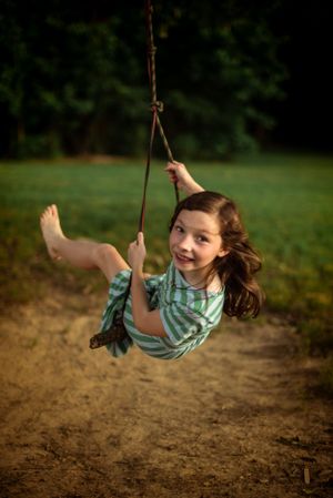 Memphis Family Photographer portrait of girl swinging at Shelby Farms during Golden Hour.