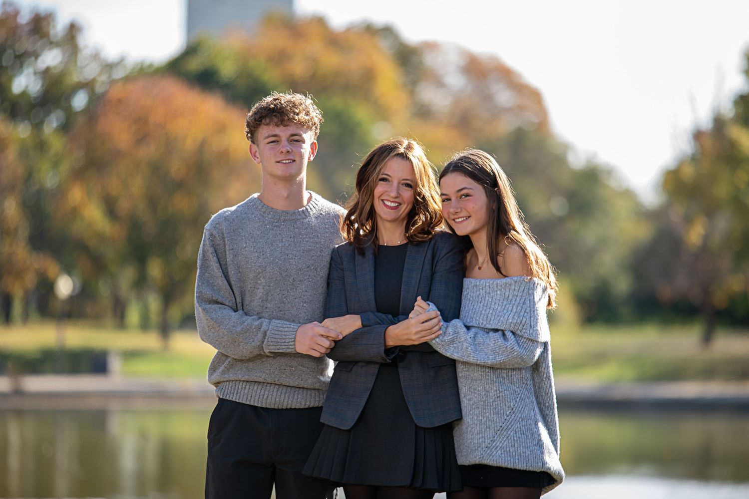 Family members posing together outdoors with golden fall foliage creating a warm natural backdrop.