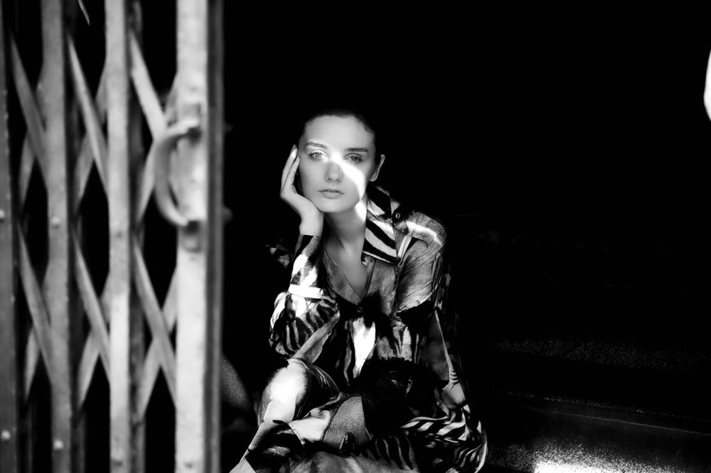 Artistic black and white portrait with dramatic shadows and geometric patterns.