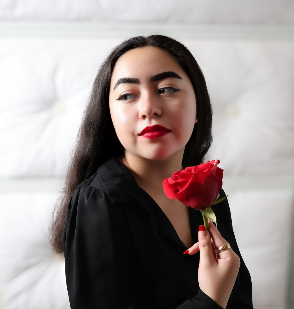 Person in black holding a red rose against white background in artistic portrait series.