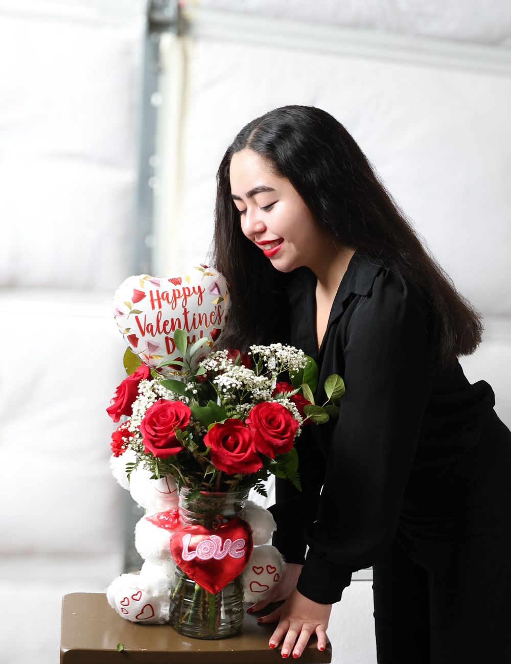 Artistic composition of red roses and Valentine's decorations on a light surface.