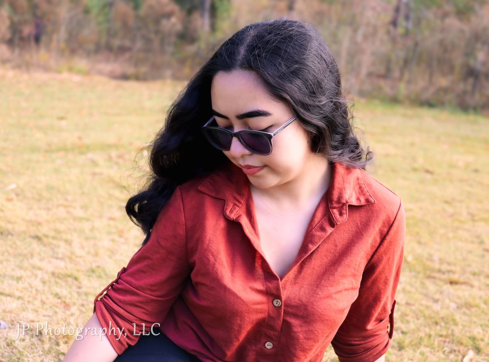 Woman in coral blazer poses outdoors during a professional photoshoot.