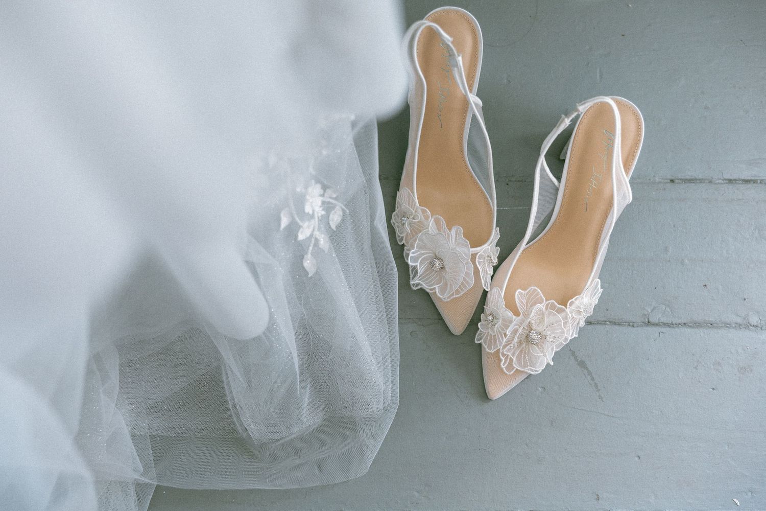 Delicate white bridal shoes with lace details and tulle fabric.