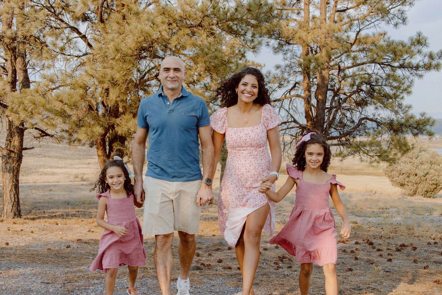 Four black and white portrait photos of a family smiling together outdoors with trees in the background.