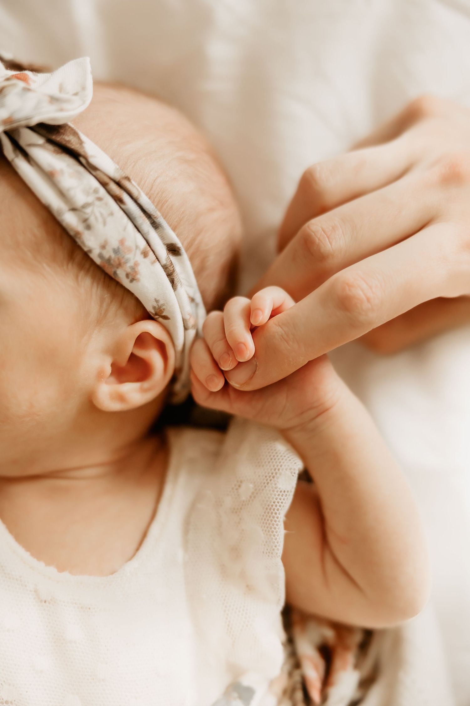 A Honolulu Newborn Photographer captures a mother holding her baby girl's finger.