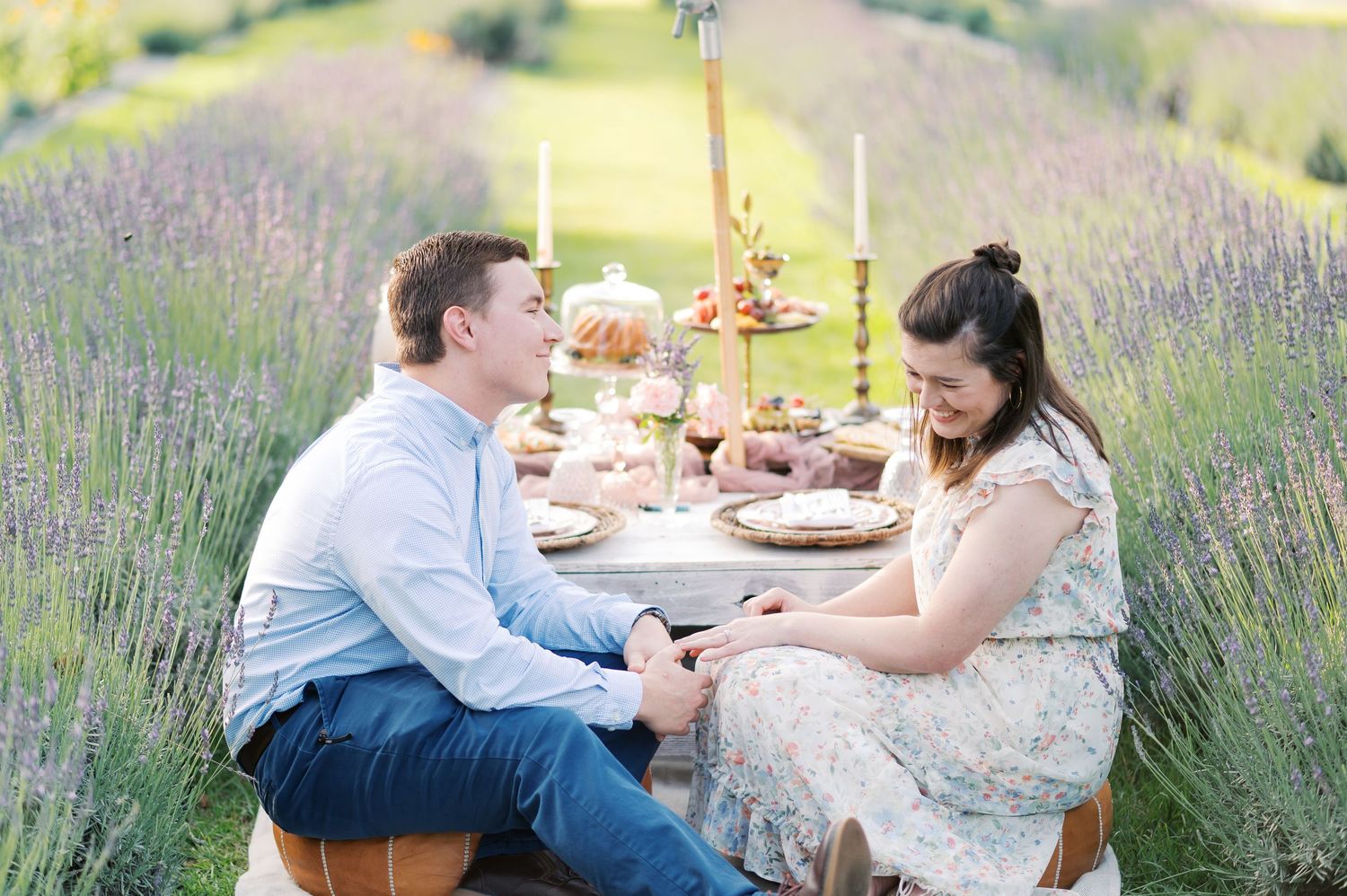 A couple in formal attire poses in a garden setting with a flowing pink tulle gown spread across the grass.