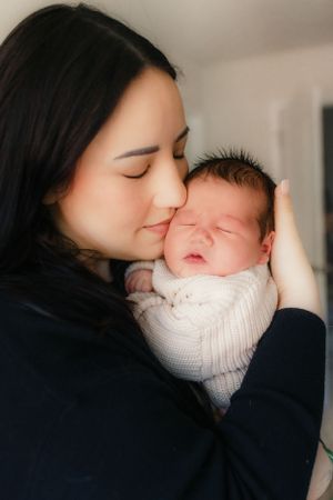 A tender moment between parent and newborn wrapped in white knitted clothing.