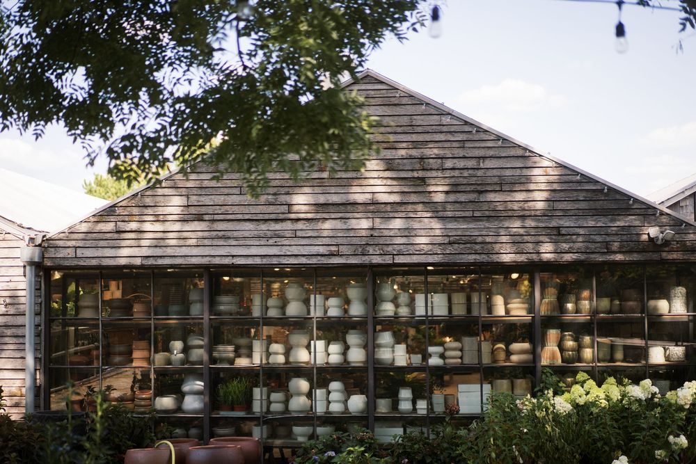 Rustic wooden ranch building with large windows stretches across a tree-lined landscape under natural lighting.
