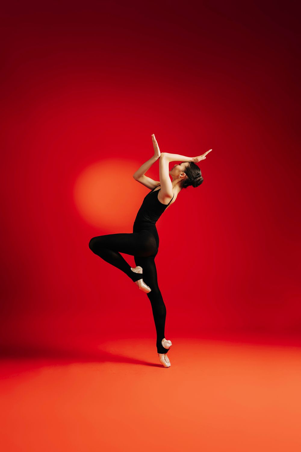 Dynamic dancer in black performs graceful leaps and poses against vibrant red studio backdrop in multiple shots.