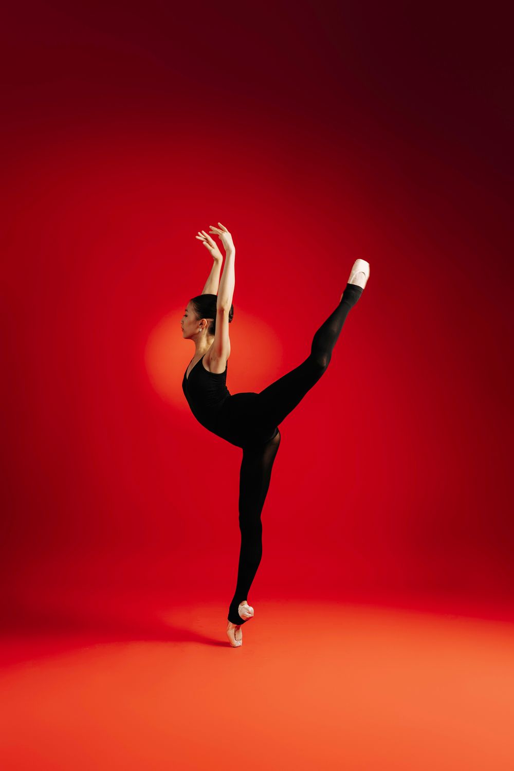 Graceful dancer in black performs a series of dramatic aerial poses against a vibrant red backdrop in a photo sequence.