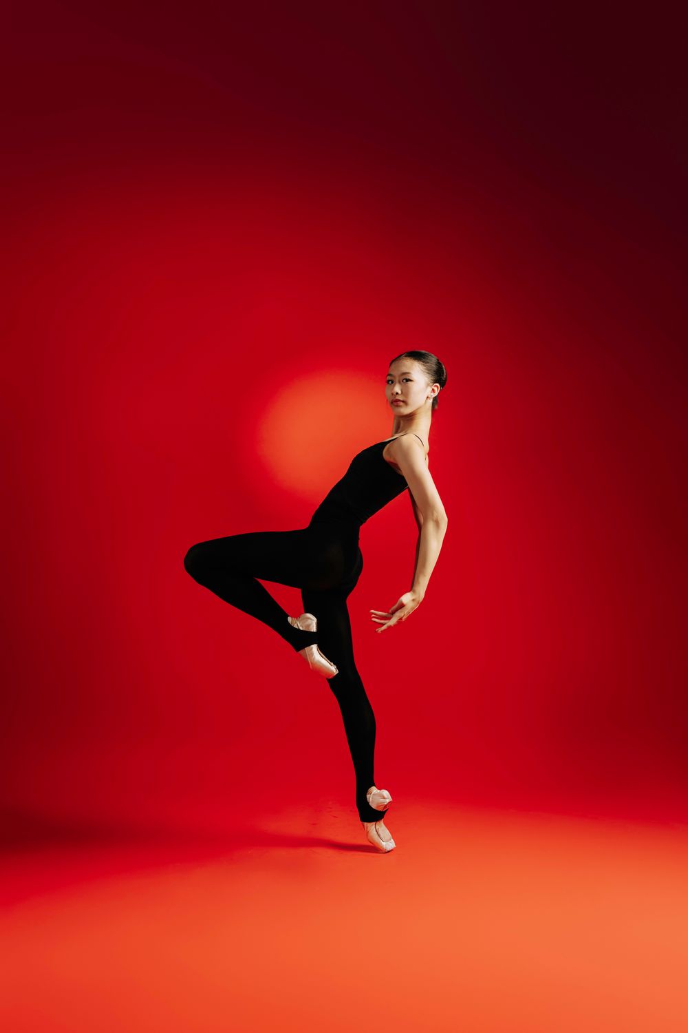 A dancer in black attire performs dynamic movements against a vibrant red background in a sequence of poses.