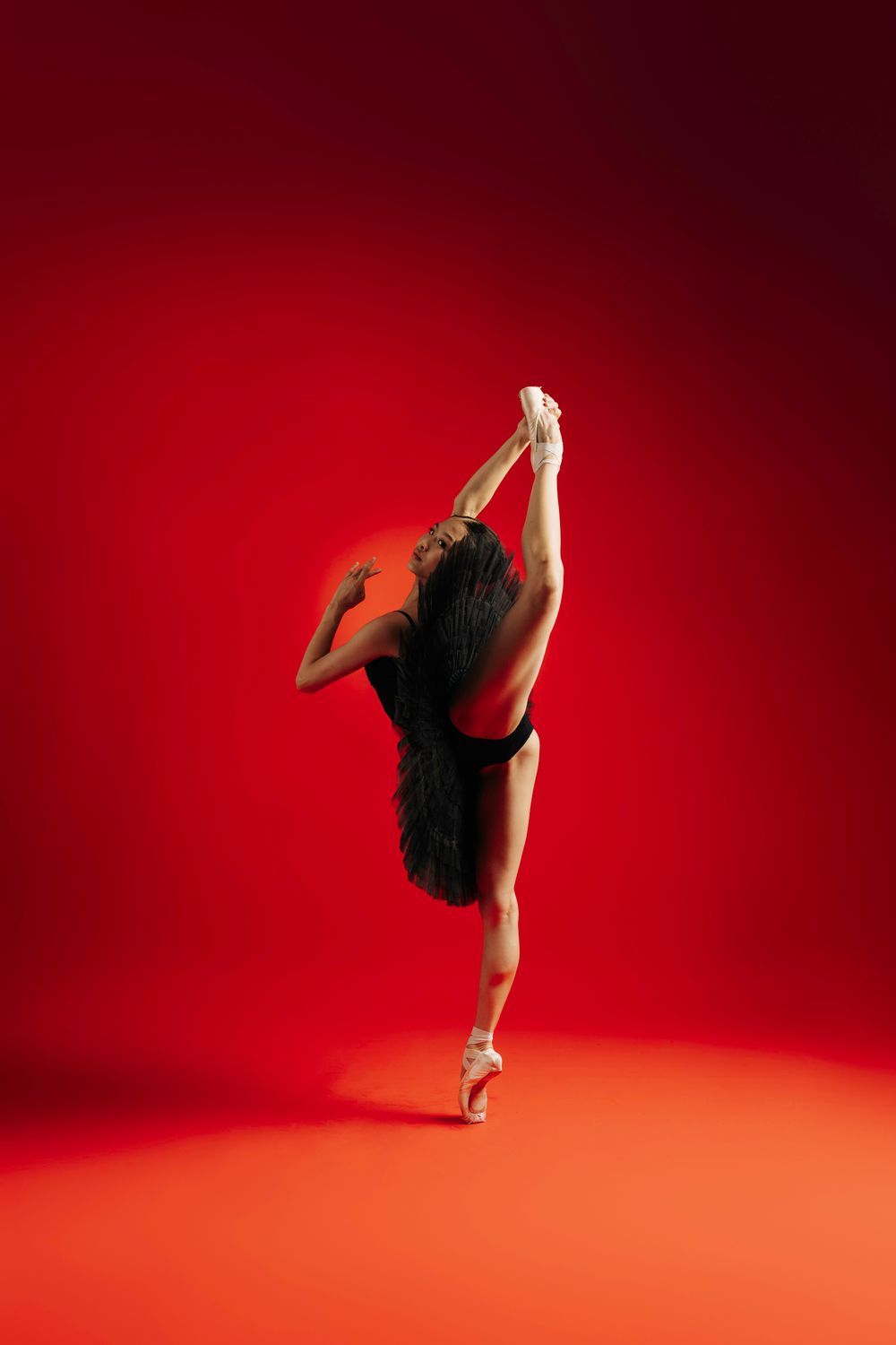 Silhouetted dancer performs graceful movements against vibrant red backdrop in dynamic sequence of poses.