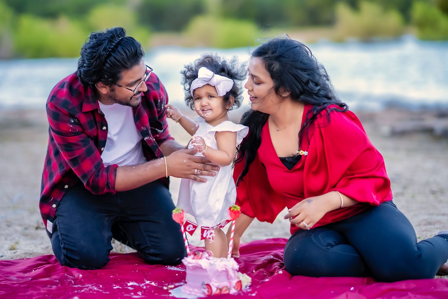Family enjoying time together on the beach near sunset in casual attire, smiling and embracing each other.