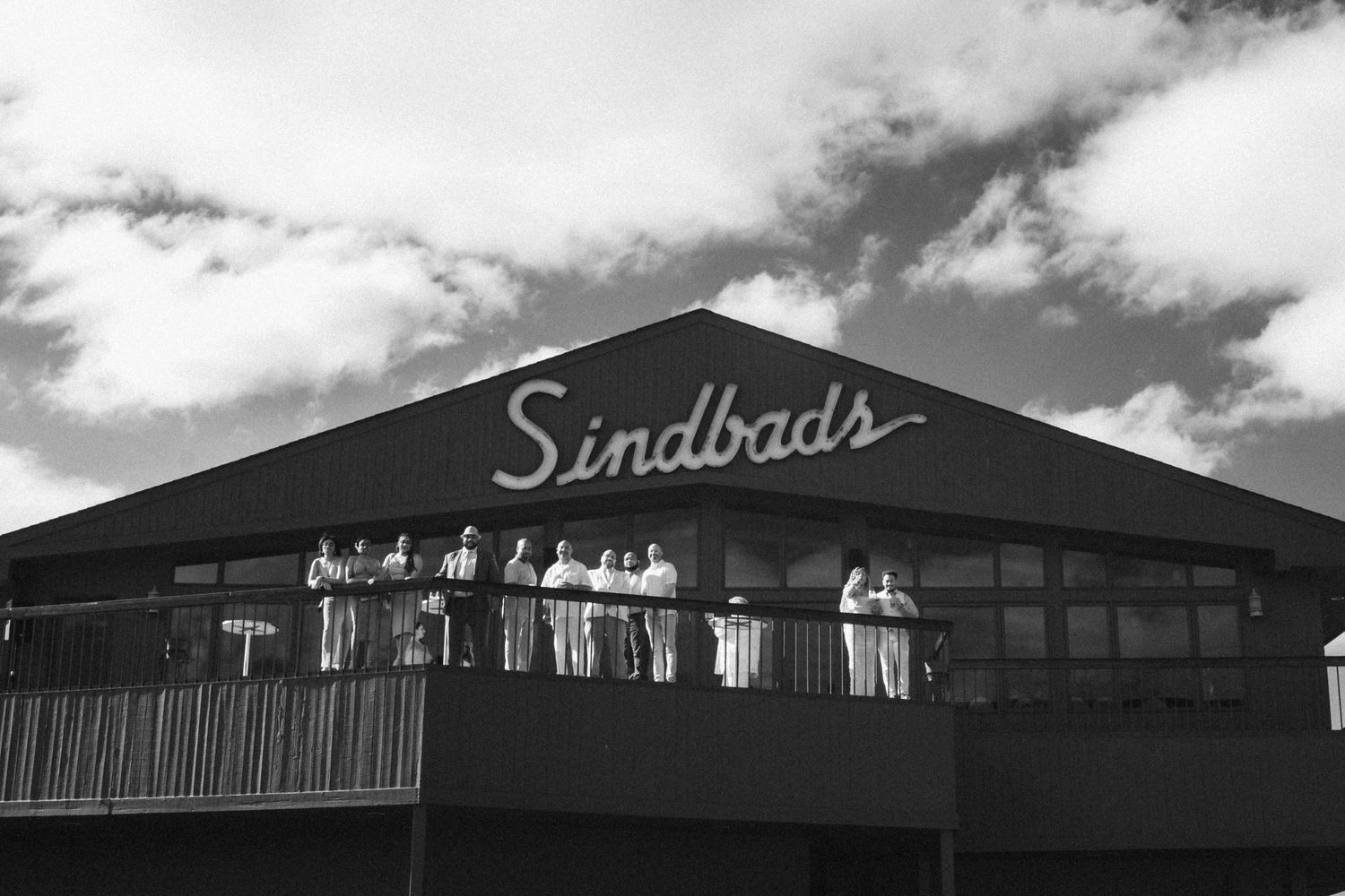 A group of people pose for a black and white portrait at an event on the balcony of Sinbad's in Detroit