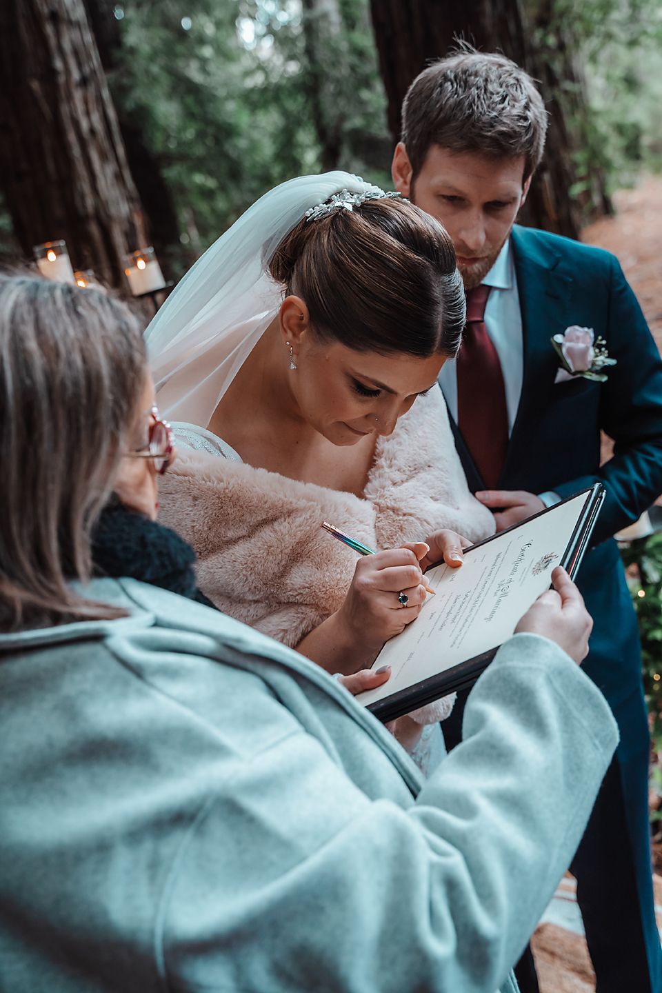 A series of photos showing bride and groom reviewing documents during a wedding ceremony in a wooded setting.
