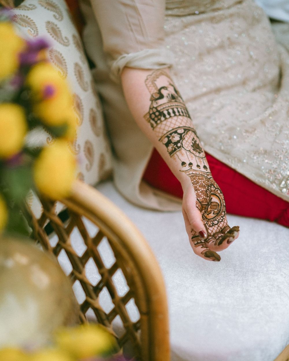 Detailed view of ornate henna designs on hands against white fabric.