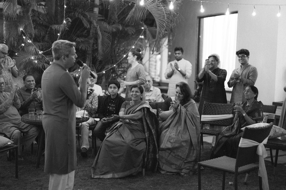 Group of people gathered at a nighttime outdoor event with string lights overhead.