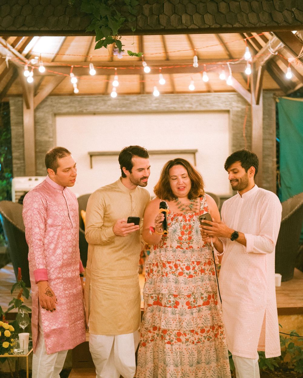 Group celebrating at an outdoor venue decorated with string lights and wearing festive attire.